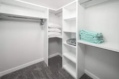 a walk in closet with white shelves and towels at Near Downtown, Large 3BR! FREE Banff Pass, Netflix, Parking! in Calgary