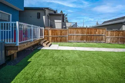 a backyard with a wooden fence and green grass at Near Downtown, Large 3BR! FREE Banff Pass in Calgary