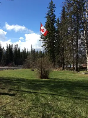 a canadian flag on a pole in a field at Tete Jaune Lodge in Tete Jaune Cache
