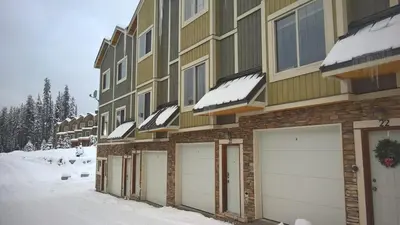 a building with two garage doors in the snow at BigWhite Ski In-Out Chalet w Priv HotTub & Garage in Big White