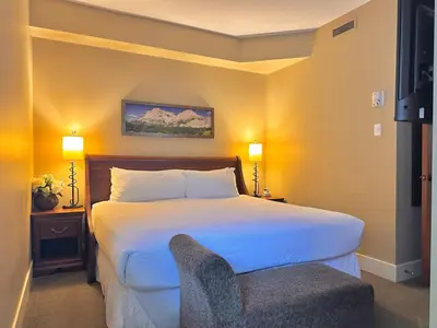 a hotel room with a bed and a chair at C111 Canmore World Class Solara Resort - Hot tub, Pool, Gym, AirCon, Free Parking & Netflix in Canmore