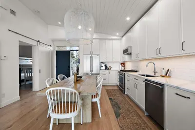 a kitchen with white cabinets and a large island with chairs at Saratoga Beachfront Villa in Oyster Bay