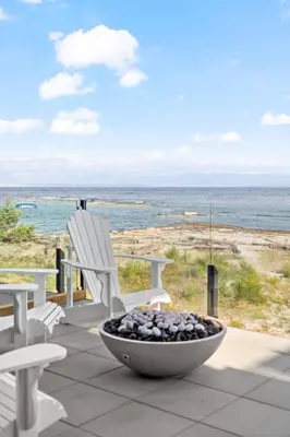 a patio with a fire pit and chairs and the ocean at Saratoga Beachfront Villa in Oyster Bay