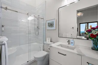 a white bathroom with a toilet and a sink at Saratoga Beachfront Villa in Oyster Bay
