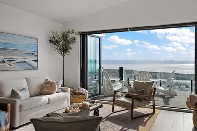 a living room with a couch and chairs and a large window at Saratoga Beachfront Villa in Oyster Bay