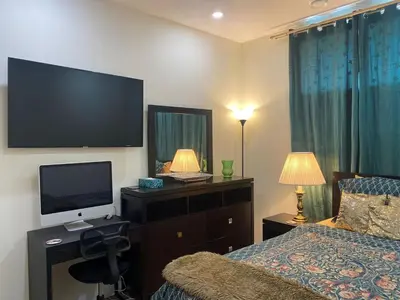 a bedroom with a television and a bed and a desk at Charming Oasis Tranquil Suite 8 min Airport, AC in Calgary