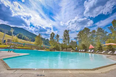 a large swimming pool with chairs and a mountain at Riverbend Townhomes by StayIn in Panorama