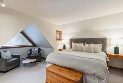 a bedroom with a large bed and a chair at 2BR in Gleneagle, Heated Flooring, Wood Burning Fireplace, Shuttle to Gondola in Whistler