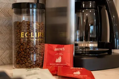 a jar of coffee beans next to a coffee maker at Modern Mountain Oasis Top floor 2 level 2bd in Canmore