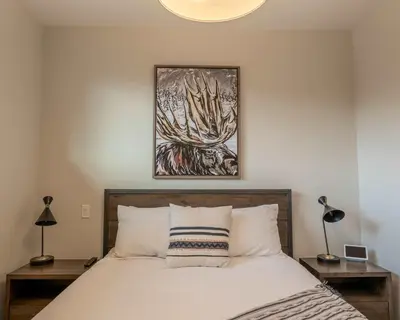 a bedroom with a bed and a painting on the wall at Modern Mountain Oasis Top floor 2 level 2bd in Canmore