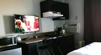 a room with a desk with a tv on the wall at Home Away Inn in Drayton Valley