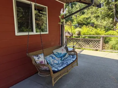 a wicker porch swing hanging from a house at Salal Forest - 2 bedroom cabin in the forest in Tofino