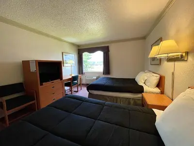 a hotel room with two beds and a television at Tamarack Inn in Rocky Mountain House