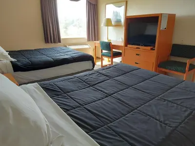 a hotel room with two beds and a television at Tamarack Inn in Rocky Mountain House
