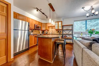 a kitchen with a stainless steel refrigerator and a couch at Greystone Lodge 224 Ski-in Out in Whistler