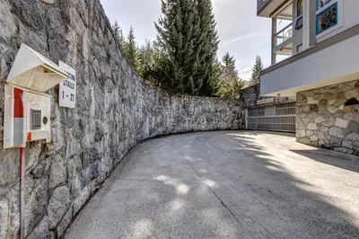 a stone wall next to a building with a driveway at Greystone Lodge 224 Ski-in Out in Whistler