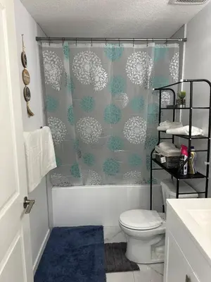 a bathroom with a shower curtain and a toilet at Muaysh Cozy Family suite - Londonderry Mall in Edmonton