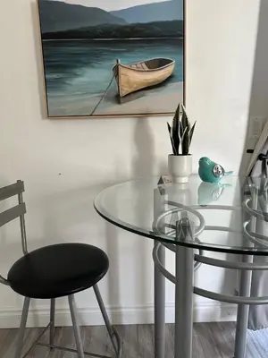a glass table with a chair and a boat on the wall at Westshore Garden Escape in Victoria