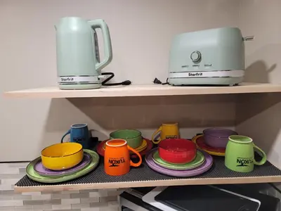 a shelf with colorful cups and plates and a toaster at The Suite Treat in Whitehorse