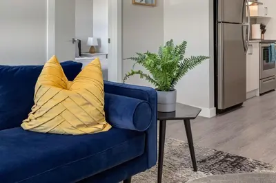 a blue couch with a yellow pillow on a table at Pet Friendly 2 Bed Close to Downtown in Calgary