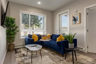 a living room with a blue couch and two windows at Pet Friendly 2 Bed Close to Downtown in Calgary