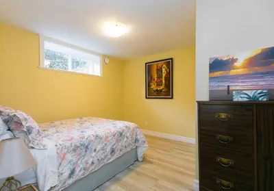 a bedroom with a bed and a dresser and a window at 2 BR Spacious Ground Level Suite in Victoria