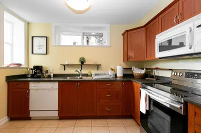 a kitchen with wooden cabinets and a sink and a microwave at 2 BR Spacious Ground Level Suite in Victoria