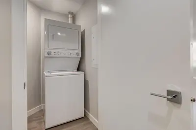 a kitchen with a washer and dryer next to a door at Free Underground Parking, Pet Friendly Apartment in Calgary