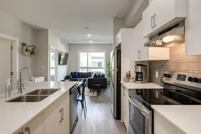 a kitchen with white counter tops and a living room at Free Underground Parking, Pet Friendly Apartment in Calgary