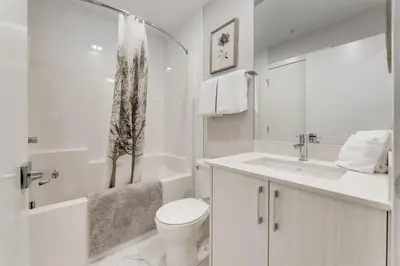 a white bathroom with a toilet and a sink at Free Heated Parking, Quick DT Access in Calgary