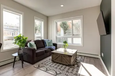 a living room with a brown couch and two windows at Free Heated Parking, Close to DT, Pet Friendly in Calgary
