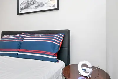 a bed with a blue and red striped pillow and a table at Home away from Home in Victoria