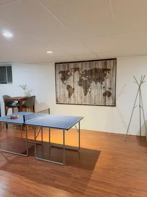 a ping pong table in a room with a map on the wall at Covepark house in Calgary