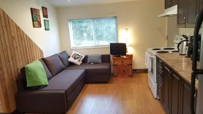 a living room with a couch in a kitchen at Cozy Quiet Suite with Private Hot Tub with Ocean Views in Nanaimo
