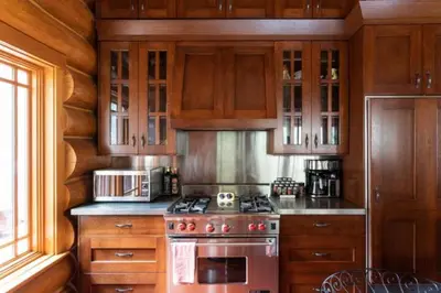 a kitchen with wooden cabinets and a stove top oven at Ravenwood Cabin by StayIn in Panorama