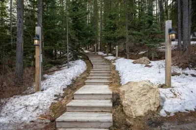 a set of stairs in a forest with snow at Ravenwood Cabin by StayIn in Panorama