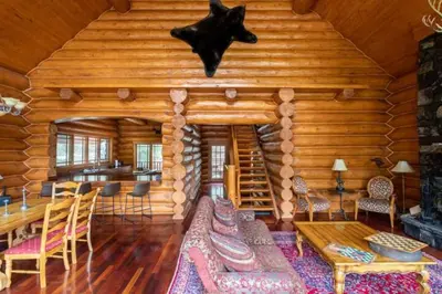 a log cabin living room with a table and a fireplace at Ravenwood Cabin by StayIn in Panorama