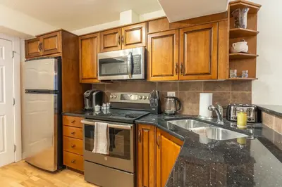 a kitchen with wooden cabinets and stainless steel appliances at Alpine Village Condo by Canadian Rockies Vacation Rentals in Canmore