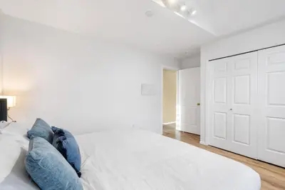 a white bedroom with a large bed with blue pillows at Spacious Family Retreat Central to YVR and Downtown in Vancouver