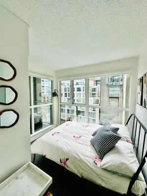 a bedroom with a bed and a large window at Beautiful condo beach side Yaletown in Vancouver
