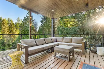 a couch on a deck with a view of trees at Elegant West Vancouver Estate with Ocean Views in West Vancouver