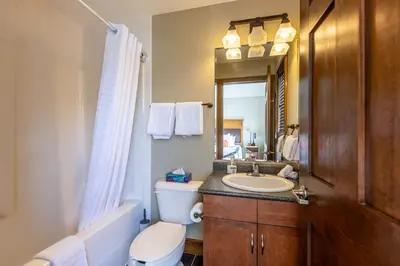 a bathroom with a sink and a toilet and a mirror at Stunning Central Canmore Condo in Canmore