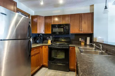 a kitchen with wooden cabinets and a stainless steel refrigerator at Stunning Central Canmore Condo in Canmore
