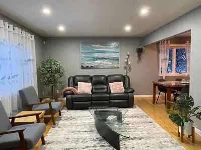 a living room with a black leather couch and a table at Welcome to Shibly's Retreat in Edmonton