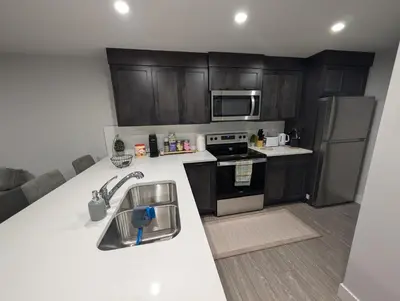 a kitchen with wooden cabinets and a white counter top at DaraJay Cozy Home in Calgary