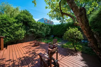a wooden deck with two chairs and a tree at Charming 3BR Home Near UBC with Parking & Backyard in Vancouver