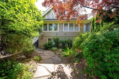 a yellow house with a pathway in front of it at Charming 3BR Home Near UBC with Parking & Backyard in Vancouver