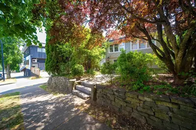 a stone retaining wall in front of a house at Charming 3BR Home Near UBC with Parking & Backyard in Vancouver