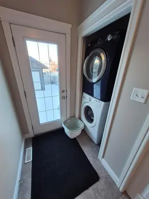 a laundry room with a washing machine next to a door at Sean Comfy Home in Edmonton