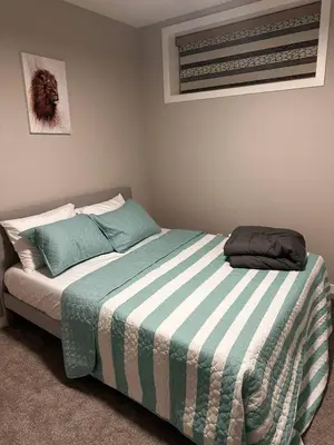 a bedroom with a bed with a blue and white blanket at Newly Built 2-Bedroom, 2 full bath Basement Suite in Calgary